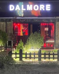 دکور داخلی کافه دالمور اسلامشهر با میزهای چوبی و نور آرام قهوه‌خانه‌ای